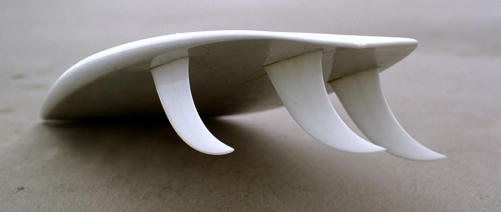 Surfboard fin types — three thruster fins on the underside of a surfboard tail